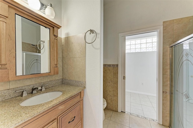 bathroom with walk in shower, tile patterned floors, toilet, tile walls, and vanity