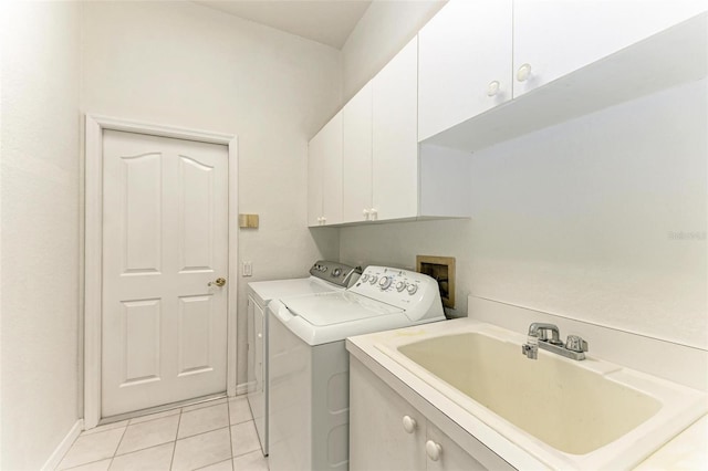 washroom featuring sink, washing machine and dryer, cabinets, and light tile patterned flooring