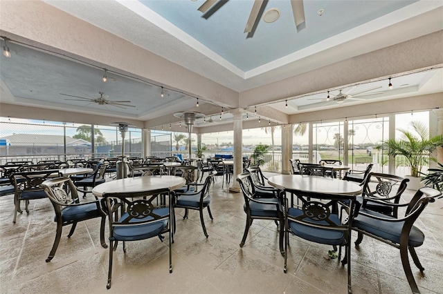 sunroom / solarium featuring a tray ceiling, a wealth of natural light, and ceiling fan