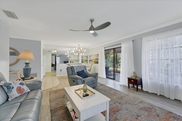 living room featuring ornamental molding, ceiling fan with notable chandelier, and light wood-type flooring