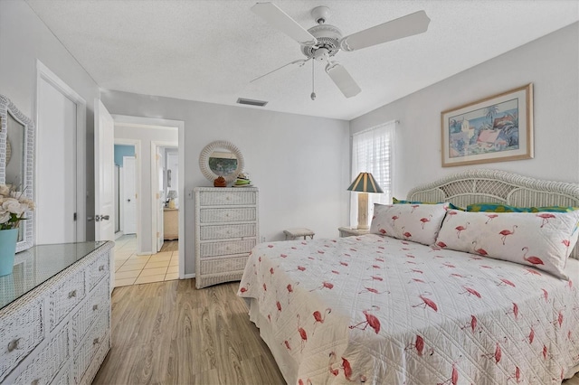 bedroom featuring ceiling fan, a textured ceiling, and light wood-type flooring