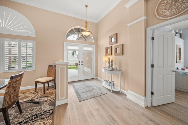 foyer entrance with crown molding, a towering ceiling, light hardwood / wood-style flooring, and french doors