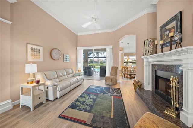 living room featuring crown molding, ceiling fan, a fireplace, and light hardwood / wood-style flooring