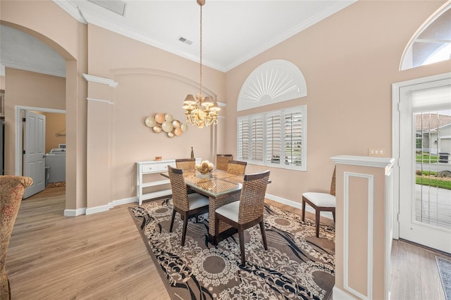 dining room featuring ornamental molding, washer / clothes dryer, a chandelier, and light wood-type flooring