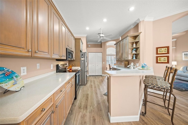 kitchen with a breakfast bar, ornamental molding, appliances with stainless steel finishes, kitchen peninsula, and light hardwood / wood-style floors