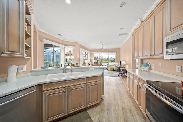 kitchen with sink, crown molding, appliances with stainless steel finishes, hanging light fixtures, and light wood-type flooring