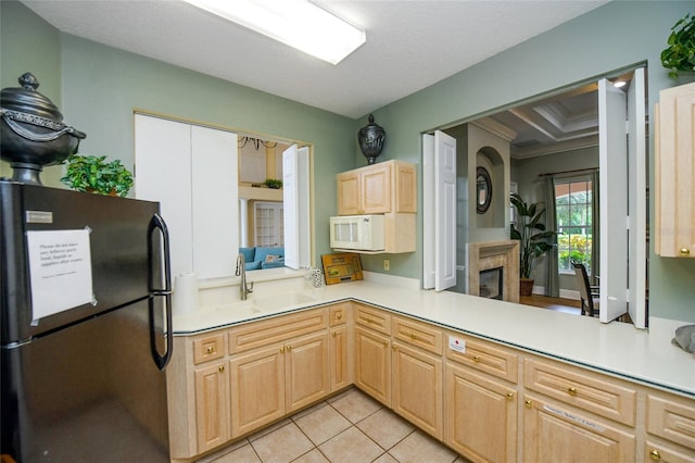 kitchen with sink, black fridge, light tile patterned flooring, light brown cabinetry, and kitchen peninsula