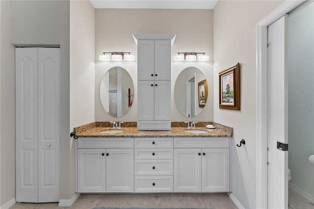 bathroom featuring a closet, a sink, toilet, and double vanity