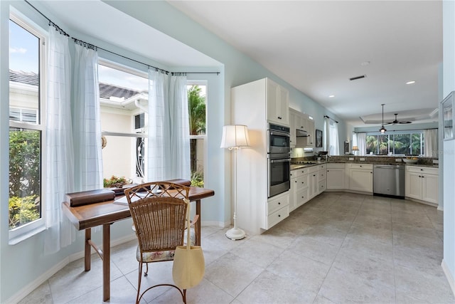 kitchen featuring stainless steel appliances, dark countertops, white cabinets, and baseboards