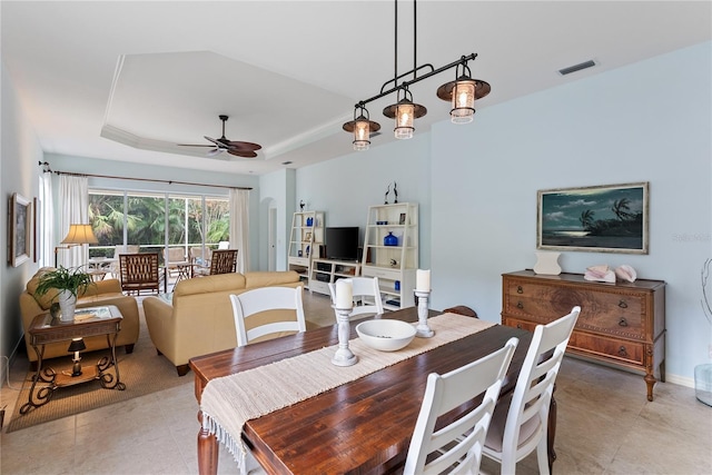 dining space featuring a tray ceiling, visible vents, light tile patterned flooring, ceiling fan, and baseboards