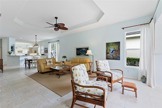 living room with ornamental molding, light tile patterned flooring, and a raised ceiling