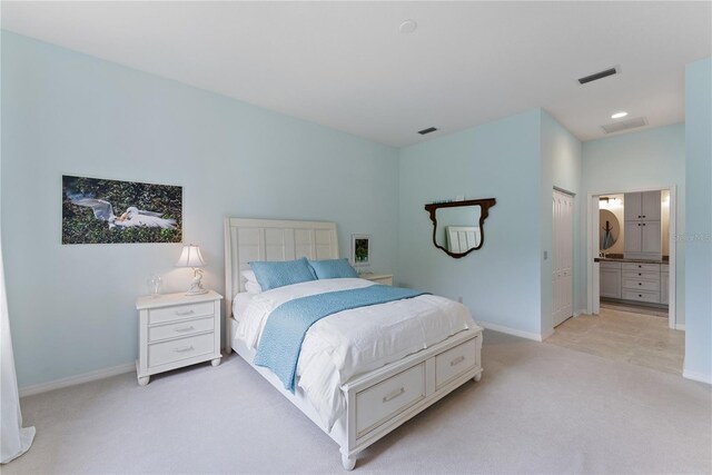 bedroom featuring light carpet, ensuite bath, visible vents, and baseboards