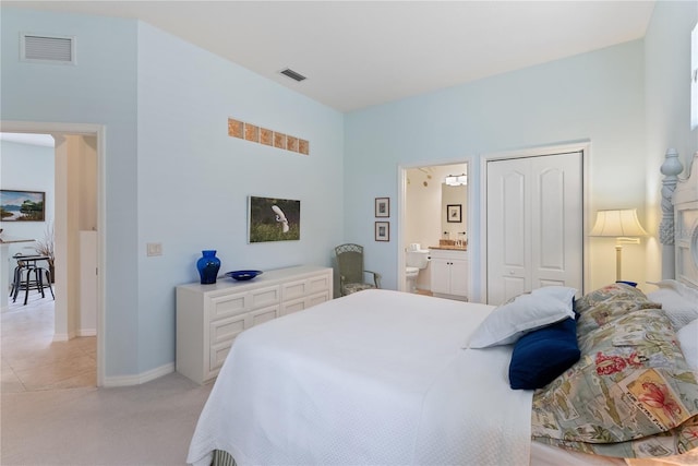 bedroom with light colored carpet, a closet, visible vents, and connected bathroom