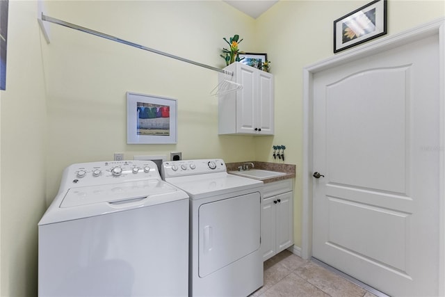 clothes washing area with cabinet space, a sink, washing machine and clothes dryer, and light tile patterned floors