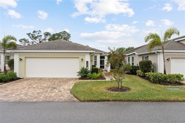 ranch-style home featuring decorative driveway, a tile roof, stucco siding, an attached garage, and a front yard