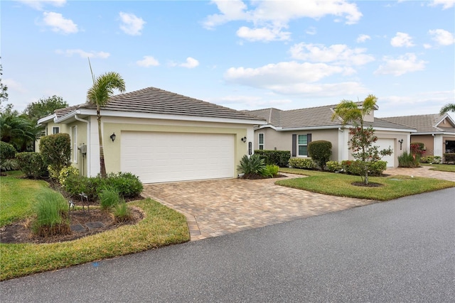 single story home featuring a tiled roof, decorative driveway, an attached garage, and stucco siding