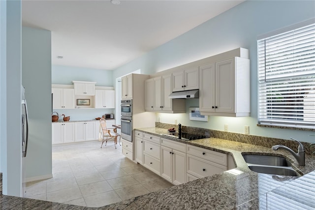kitchen featuring light tile patterned floors, black electric cooktop, a sink, under cabinet range hood, and stainless steel double oven
