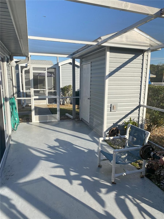 view of patio featuring glass enclosure and a storage unit