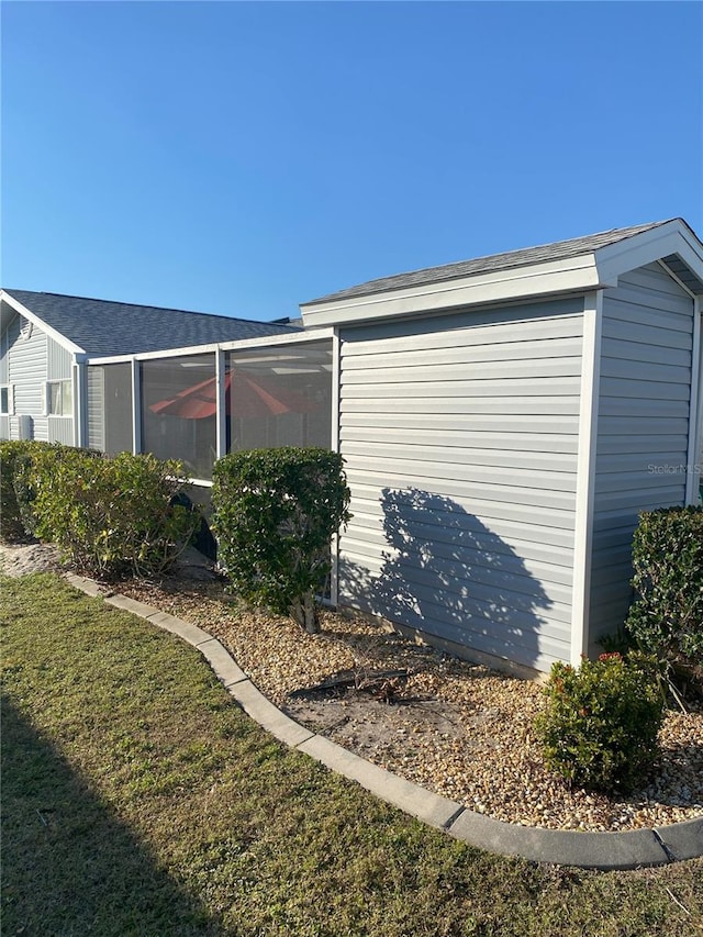 view of side of property with a sunroom and a lawn