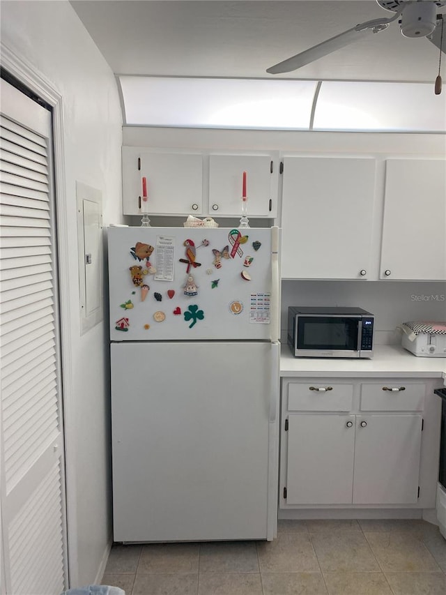 kitchen with light tile patterned flooring, white fridge, white cabinets, and electric panel