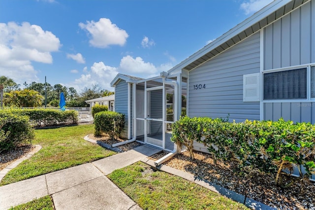 property entrance with fence, board and batten siding, and a yard