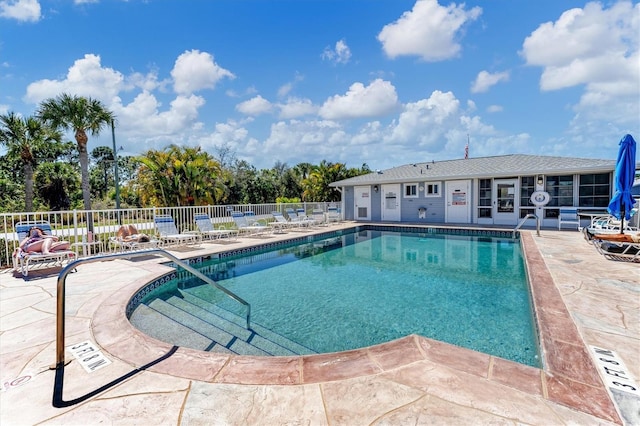 community pool with a patio area and fence