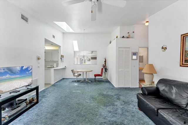 carpeted living area with vaulted ceiling with skylight, visible vents, and a ceiling fan