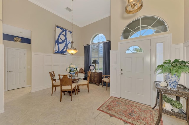 tiled foyer featuring ornamental molding and a high ceiling