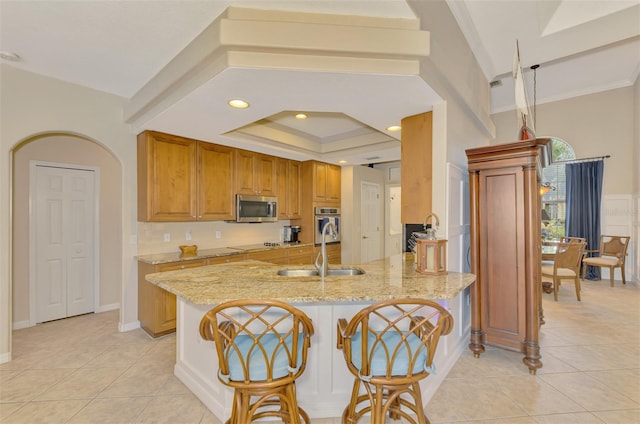 kitchen featuring sink, light stone counters, light tile patterned floors, appliances with stainless steel finishes, and kitchen peninsula