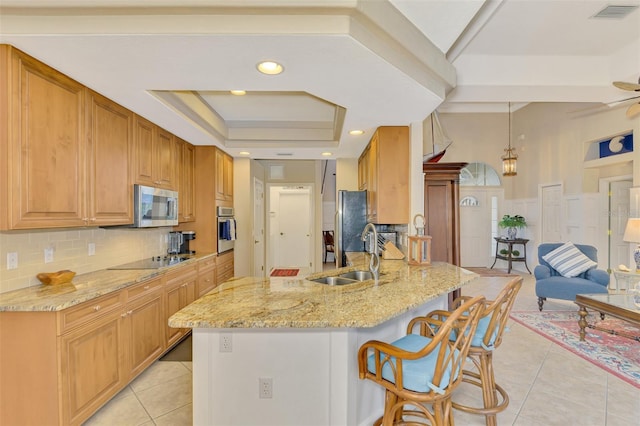 kitchen featuring sink, light tile patterned floors, a tray ceiling, stainless steel appliances, and light stone countertops