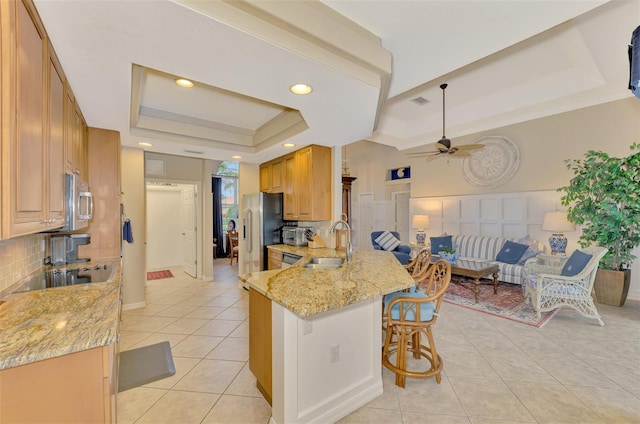 kitchen featuring sink, a kitchen breakfast bar, stainless steel appliances, kitchen peninsula, and a raised ceiling