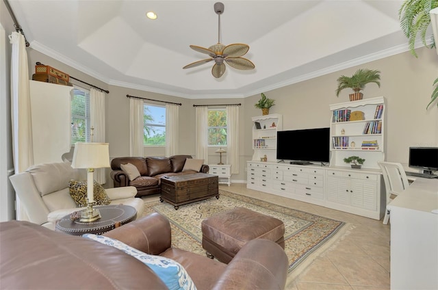 living room with light tile patterned floors, a tray ceiling, ornamental molding, and ceiling fan