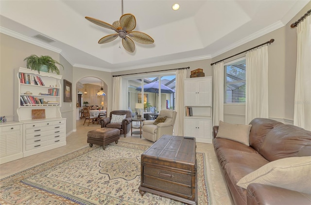 living room with crown molding, light tile patterned floors, a tray ceiling, and ceiling fan