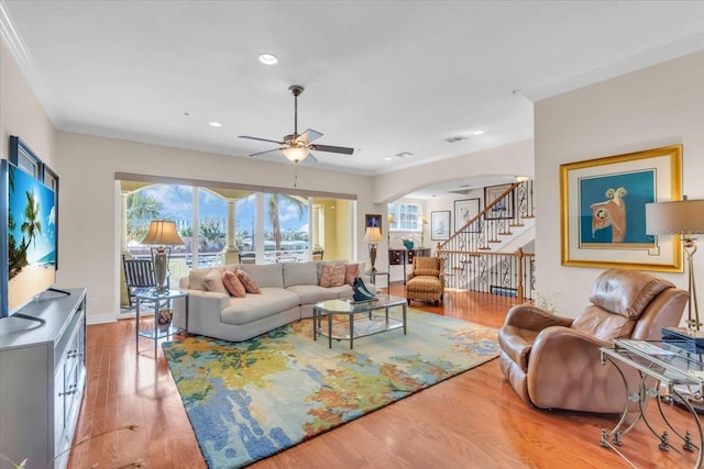 living room with hardwood / wood-style flooring, ceiling fan, and crown molding