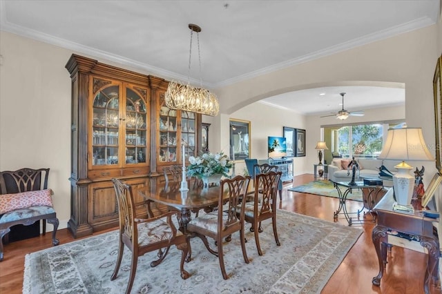 dining space with crown molding, ceiling fan with notable chandelier, and hardwood / wood-style floors