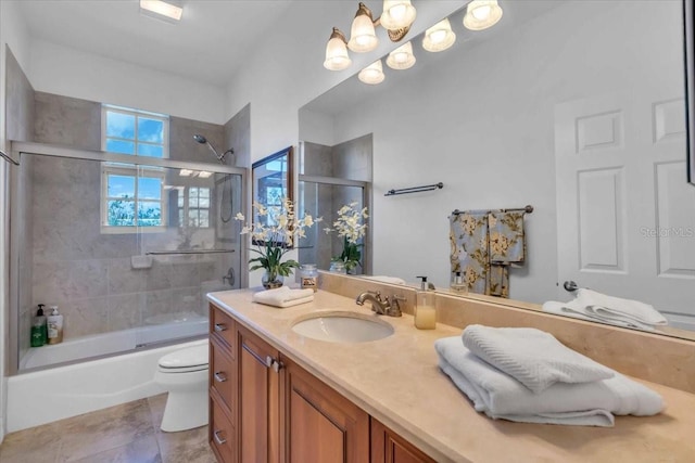 full bathroom featuring vanity, tile patterned flooring, bath / shower combo with glass door, and toilet