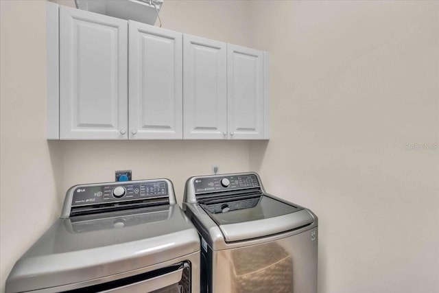 washroom with washing machine and dryer and cabinets