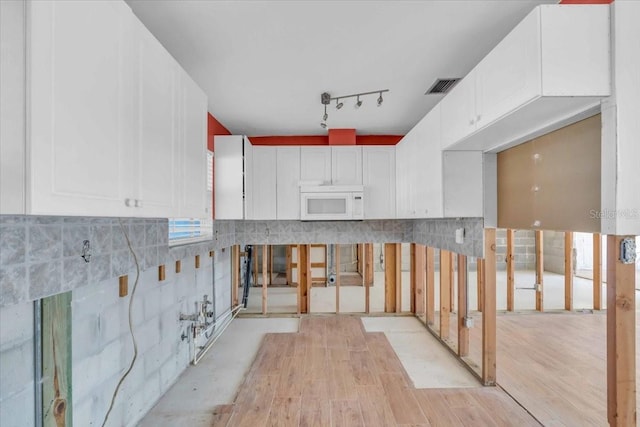 kitchen featuring white cabinetry, rail lighting, and light hardwood / wood-style floors