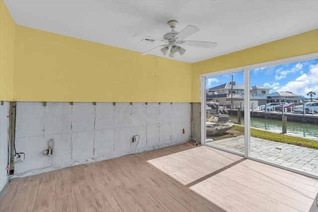 unfurnished sunroom with a water view and ceiling fan