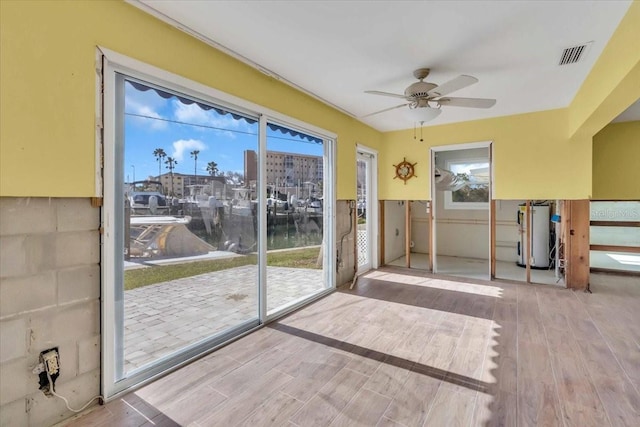 doorway to outside featuring hardwood / wood-style floors, water heater, and ceiling fan