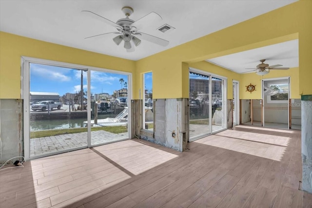 unfurnished sunroom with a water view and ceiling fan