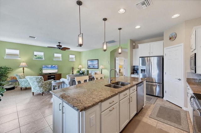 kitchen featuring sink, appliances with stainless steel finishes, light stone countertops, a kitchen island with sink, and white cabinets