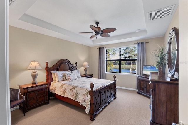 carpeted bedroom with a raised ceiling and ceiling fan