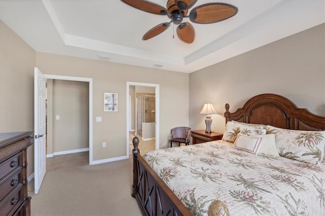 bedroom featuring light colored carpet, a raised ceiling, ceiling fan, and ensuite bathroom