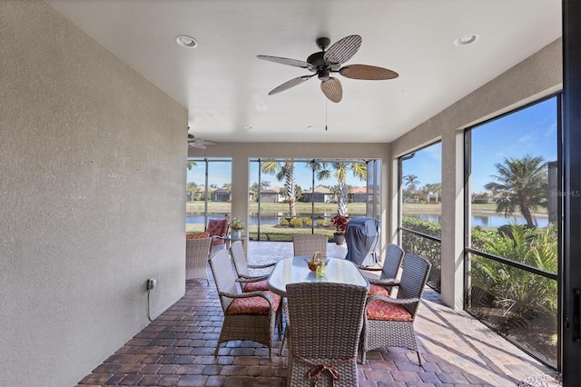 sunroom / solarium featuring a water view and ceiling fan