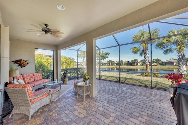 sunroom with ceiling fan and a water view