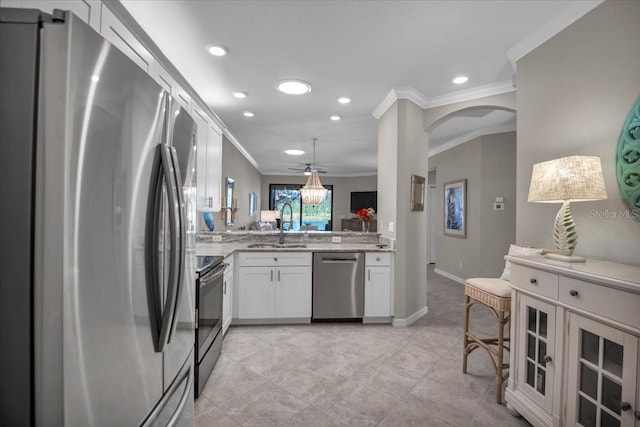 kitchen featuring sink, ornamental molding, kitchen peninsula, stainless steel appliances, and white cabinets