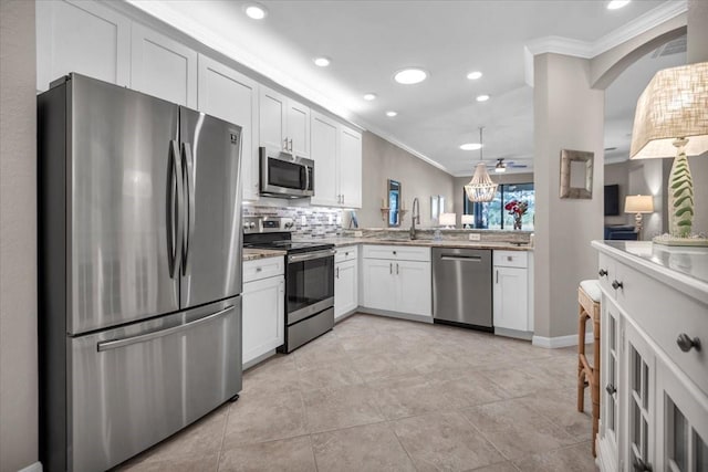 kitchen with white cabinetry, hanging light fixtures, crown molding, and stainless steel appliances