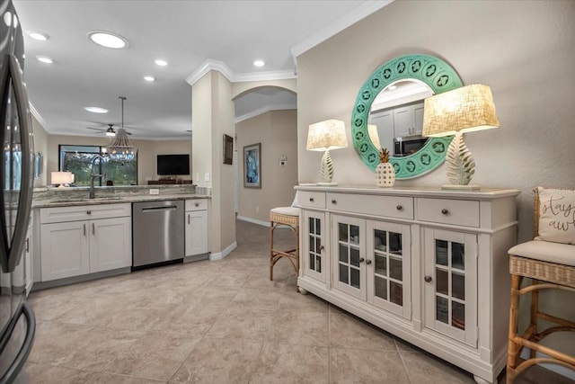 kitchen featuring appliances with stainless steel finishes, white cabinetry, sink, ornamental molding, and light stone countertops