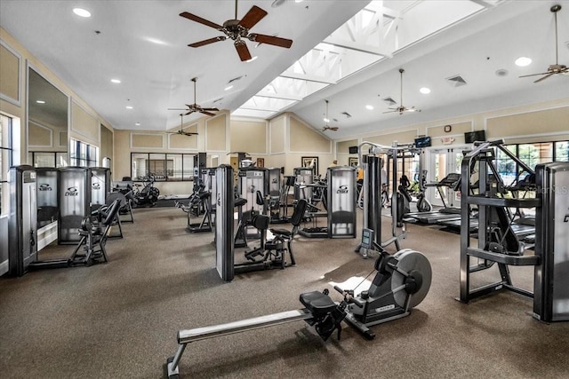 gym with lofted ceiling with skylight and ceiling fan